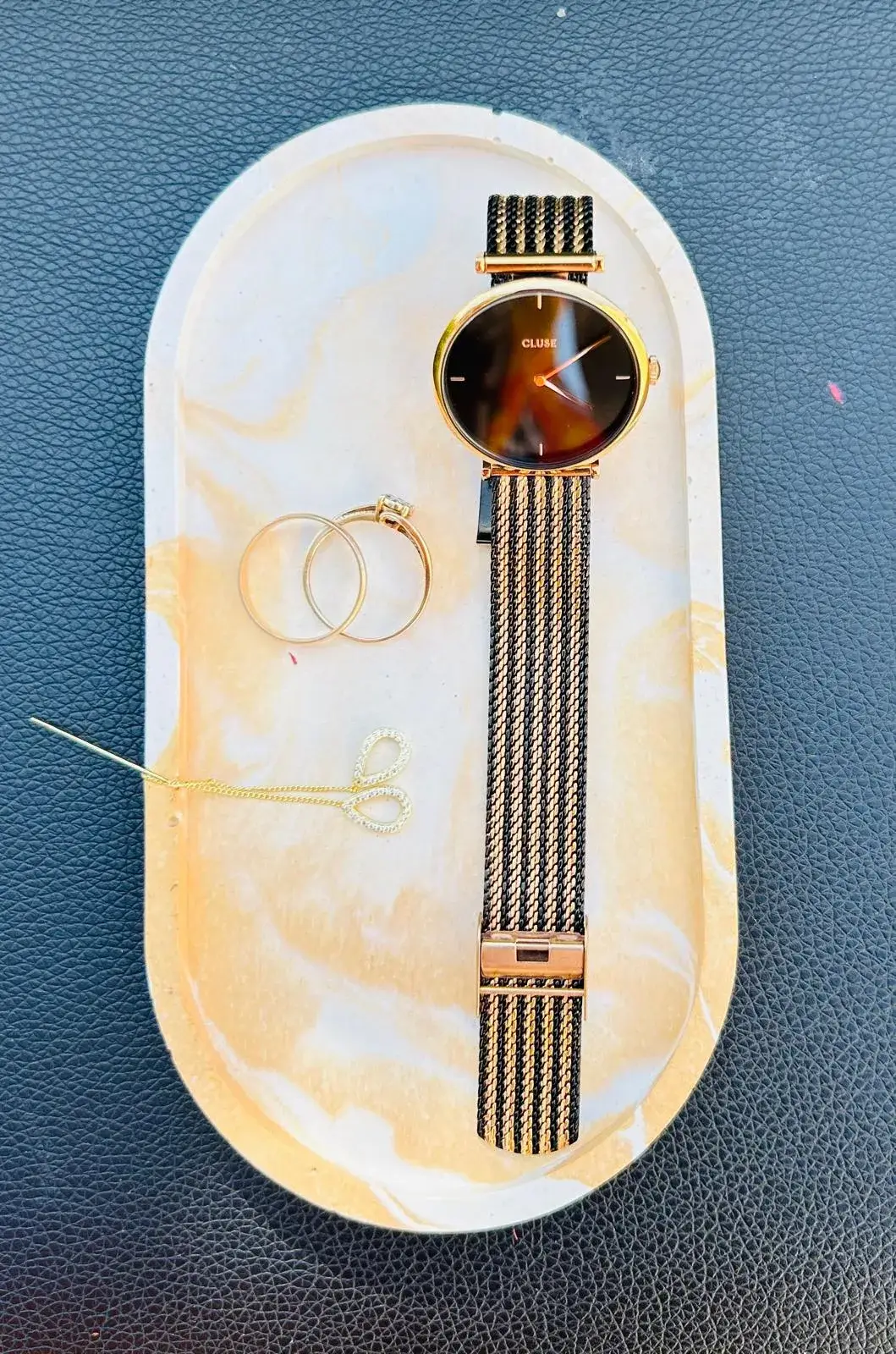 Montre dorée et bijoux sur plateau en marbre