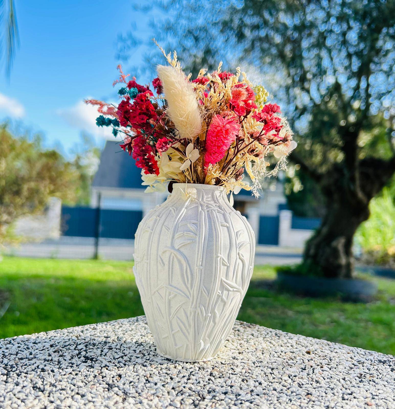 Vase blanc avec fleurs colorées à l'extérieur.