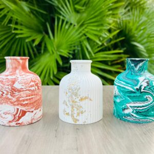Trois vases colorés sur une table en bois.